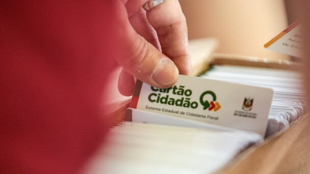 M&atilde;o retira um cart&atilde;o de uma pilha com v&aacute;rios. Nele est&aacute; escrito Cart&atilde;o Cidad&atilde;o - Sistema Estadual de Cidadania Fiscal. 