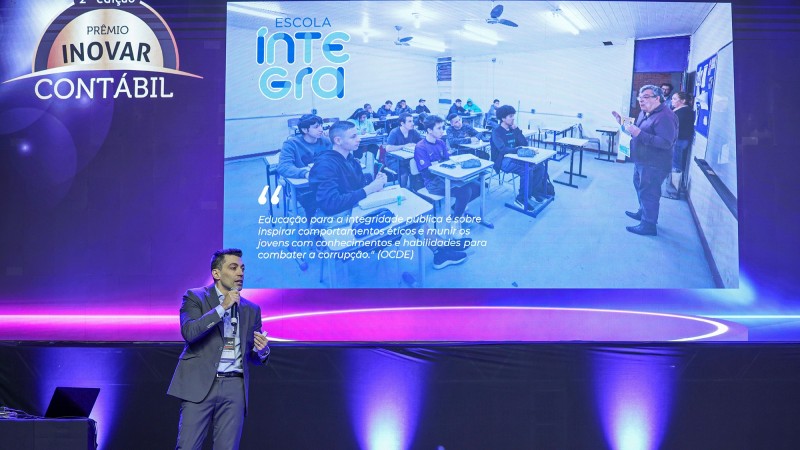 Contador e Auditor-Geral Adjunto da Contadoria e Auditoria-Geral do Estado (Cage), Jocie Rocha Pereira falando ao microfone em frente a um tel&atilde;o