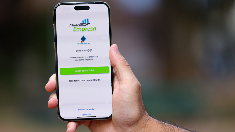 M&atilde;o segura celular. Na tela, est&aacute; o aplicativo Minha Empresa.