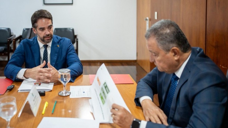 Autoridades reunidas em uma mesa, lendo documentos