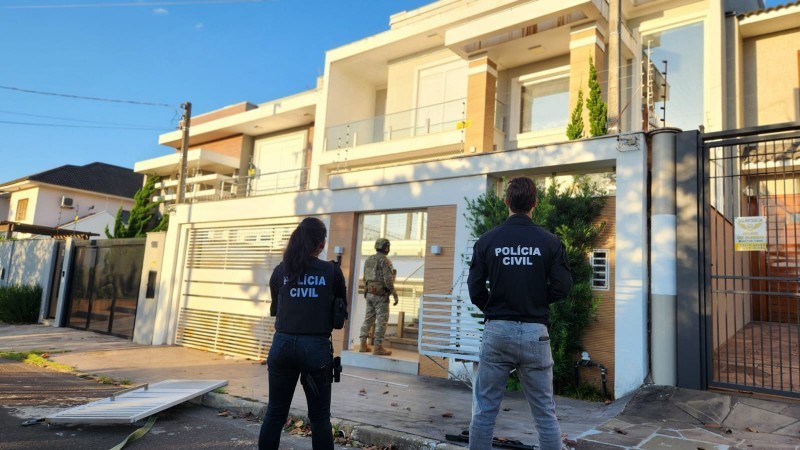 servidores da Pol&iacute;cia Civil de costas na frente de uma casa