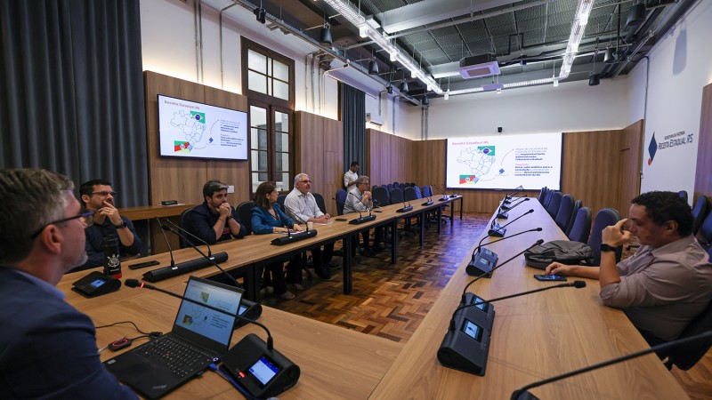 autoridades sentada ao redor de uma mesa de confer&ecirc;ncia