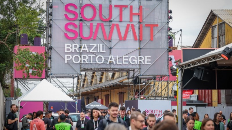 P&oacute;rtico com a inscri&ccedil;&atilde;o South Summit Brazil Porto Alegre e diversas pessoas passando por baixo dele