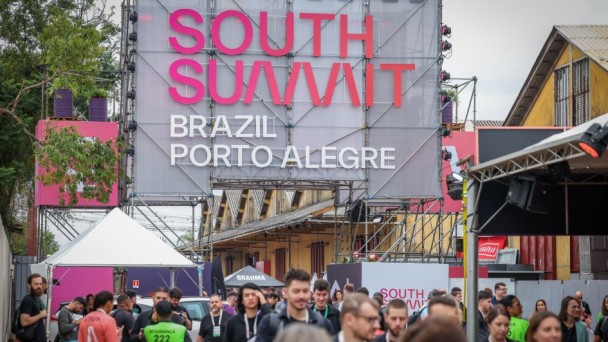 P&oacute;rtico com a inscri&ccedil;&atilde;o South Summit Brazil Porto Alegre e diversas pessoas passando por baixo dele