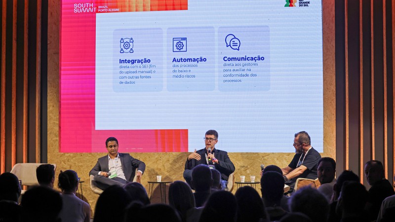 Robson Bittencourt, Jimmy Paiva Gomes e Guto Ortac est&atilde;o em um palco do South Summit. Jimmy segura o microfone.