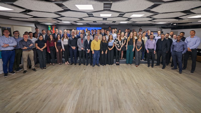 Servidores da CAGE reunidos em grupo &uacute;nico posando para a foto em uma sala com o teto com formato de hex&aacute;gonos